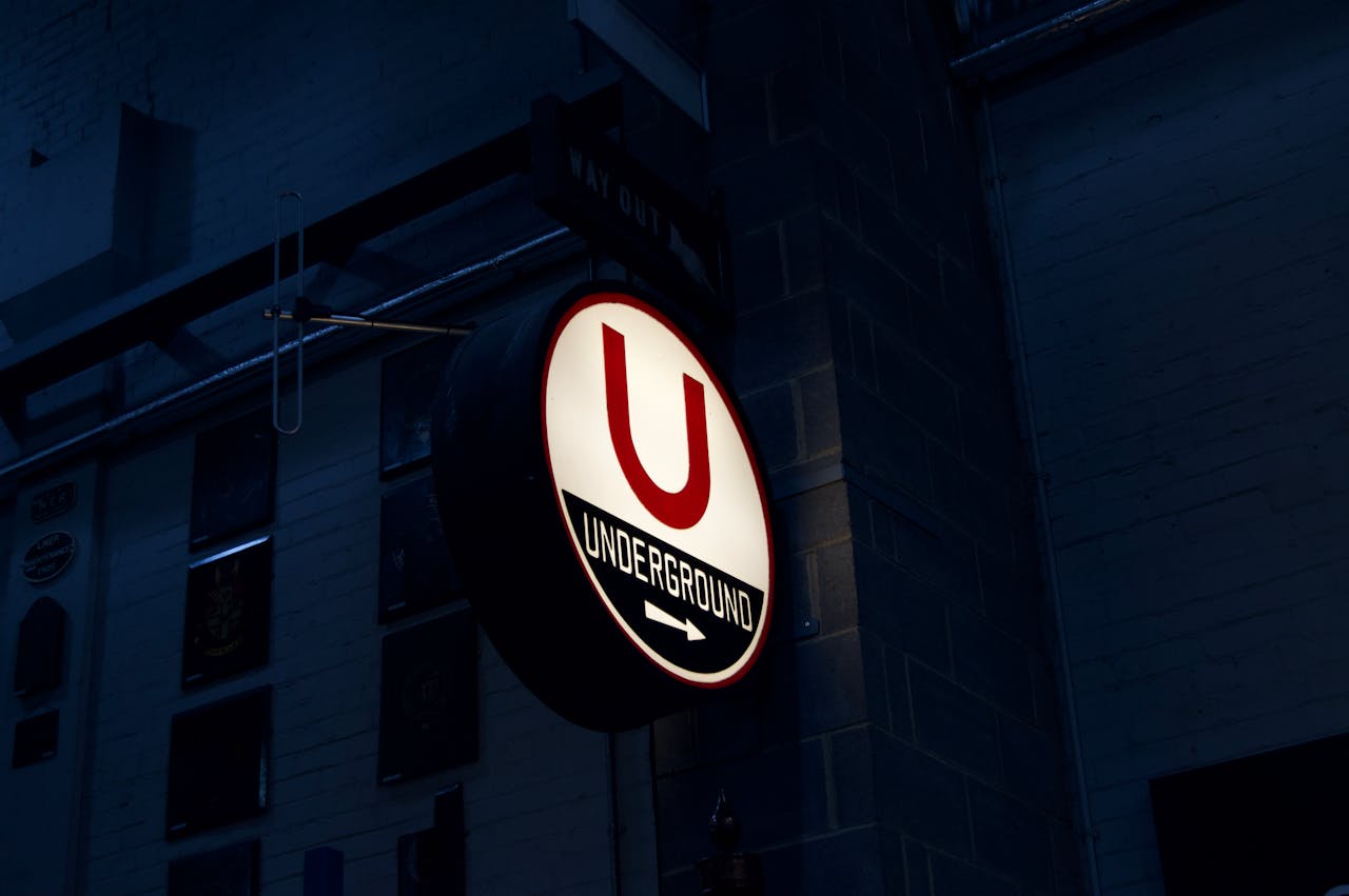 Close-up of a glowing 'Underground' sign in a dark urban setting.