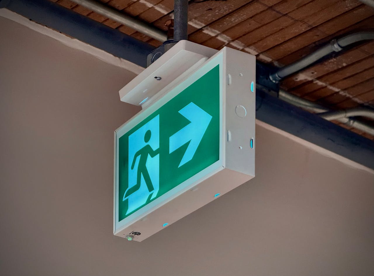 Green emergency exit sign with an arrow indicating direction inside a building.